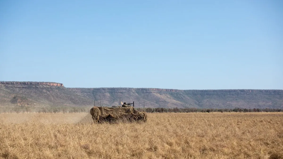 A camouflaged armoured vehicle moving across open plains during a military exercise.