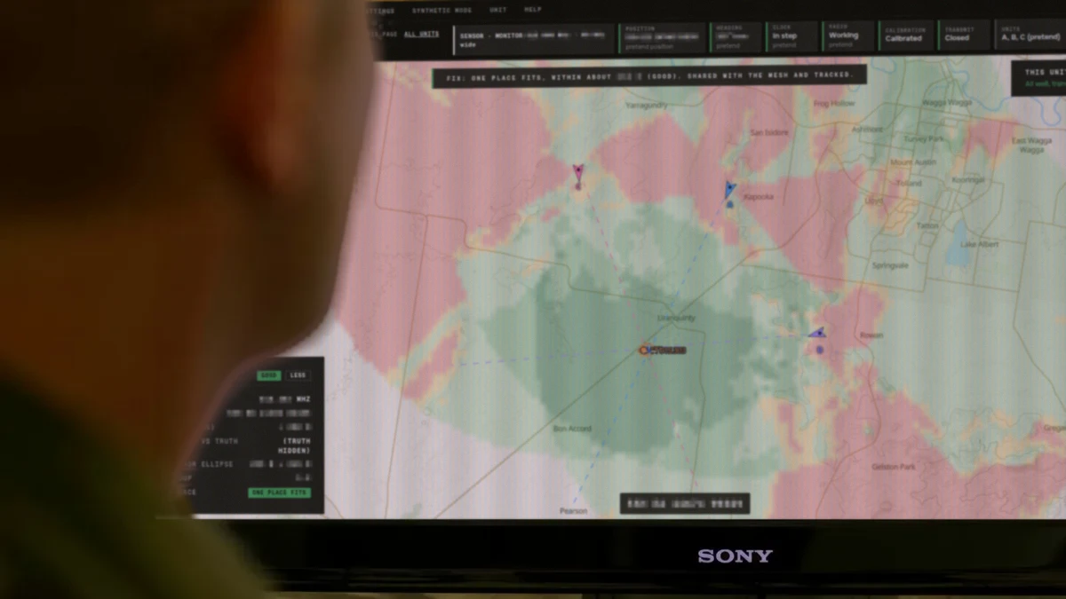 An operator watching PlatypOS on a monitor: bearing lines from three sensors meet on a located emitter over a terrain map.