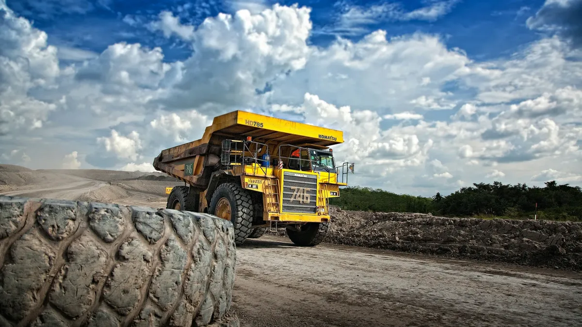 A loaded haul truck on a mine haul road below a cloudy sky.