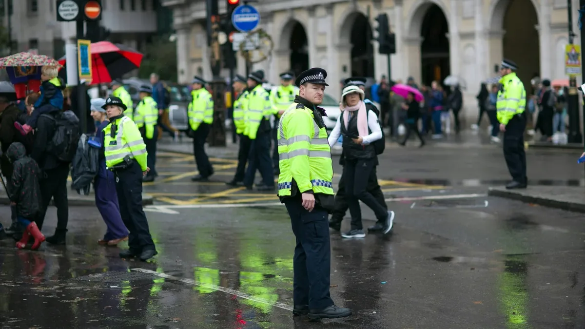 Police officers in high-visibility jackets on a wet city street.